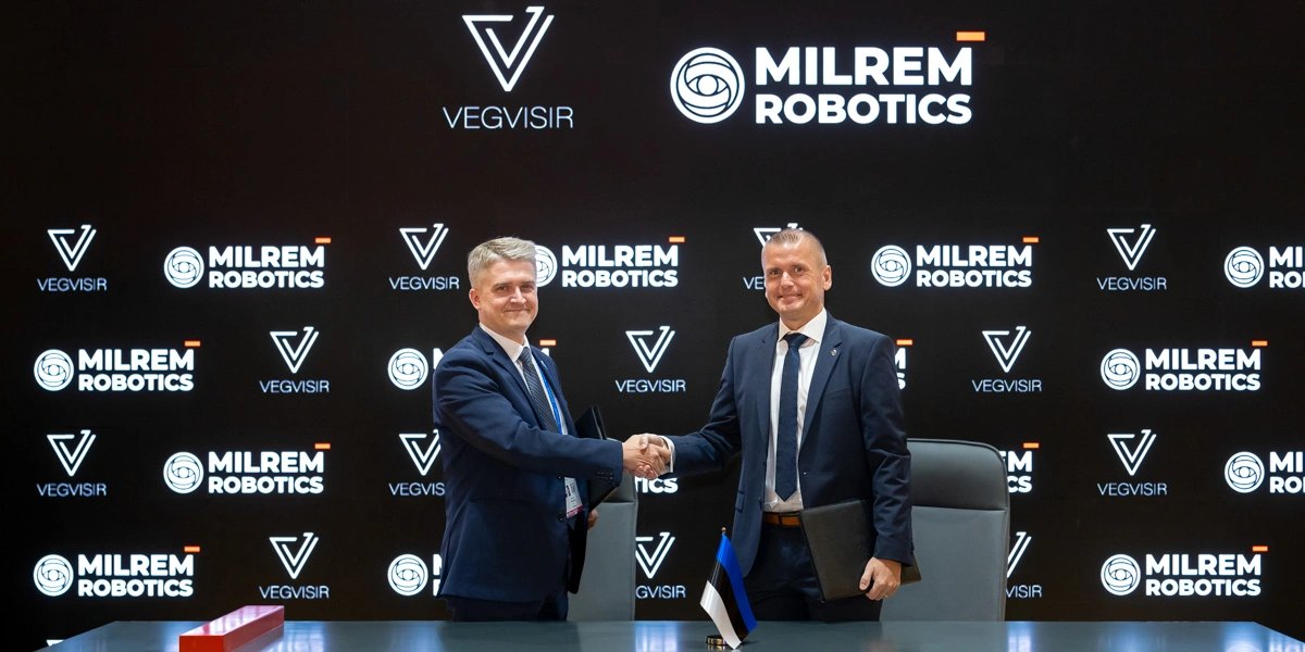 Representatives of Vegvisir and Milrem Robotics shake hands after signing the MoU at IDEX 2025, in front of both companies' logos